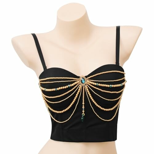 Top negro con cadenas doradas decorativas y una gema verde.