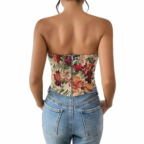 Mujer con corsé floral y jeans, vista trasera.