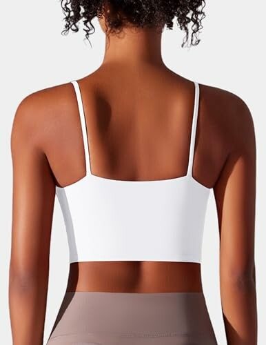 Mujer de espaldas con top blanco y cabello rizado.