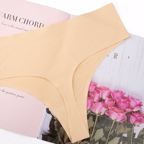 Ropa interior beige sin costuras sobre un libro con rosas.