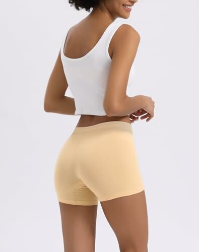 Mujer con camiseta blanca y pantalones cortos beige.